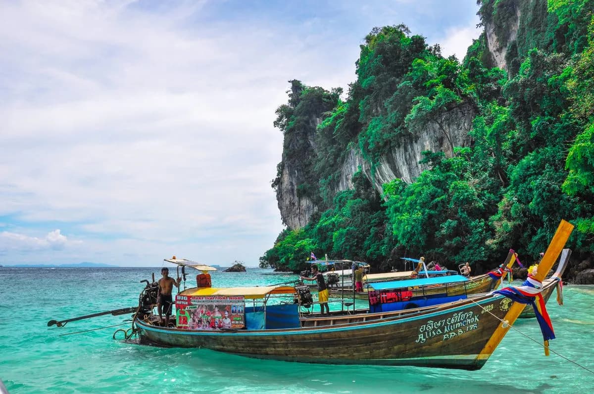 A longtail boat moored beneath limestone cliffs in Phang Nga Bay, Thailand
