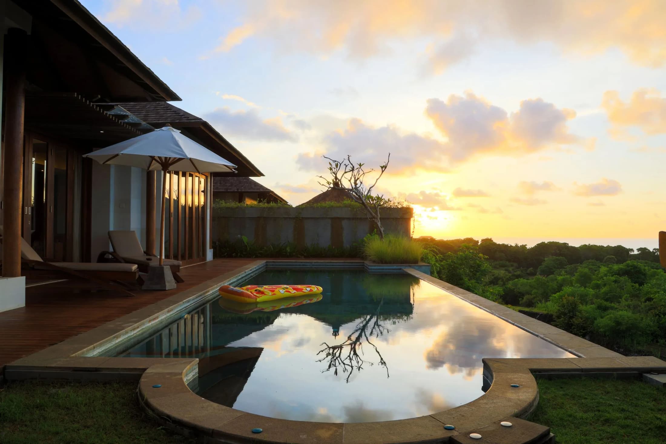 An infinity pool at a Bali villa reflecting the sunset sky
