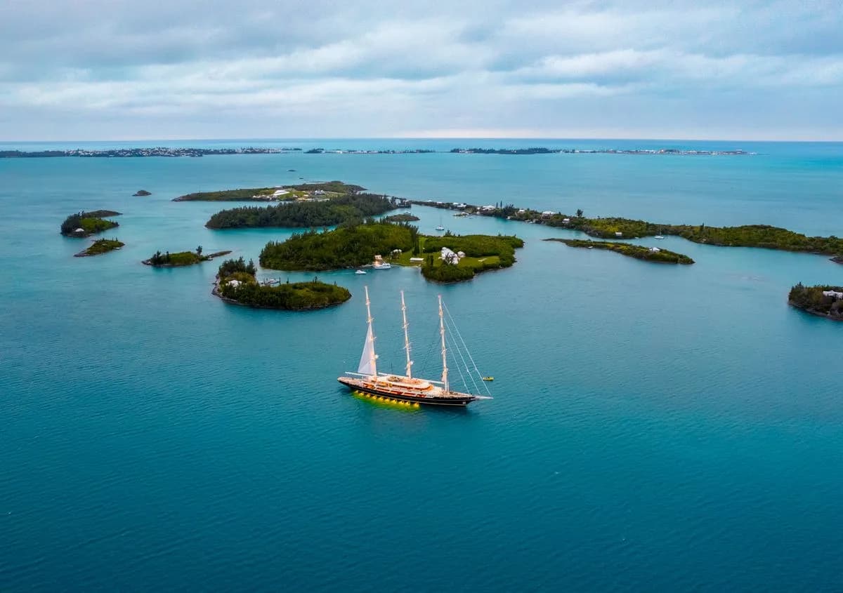 A tall sailing ship anchored among green islands
